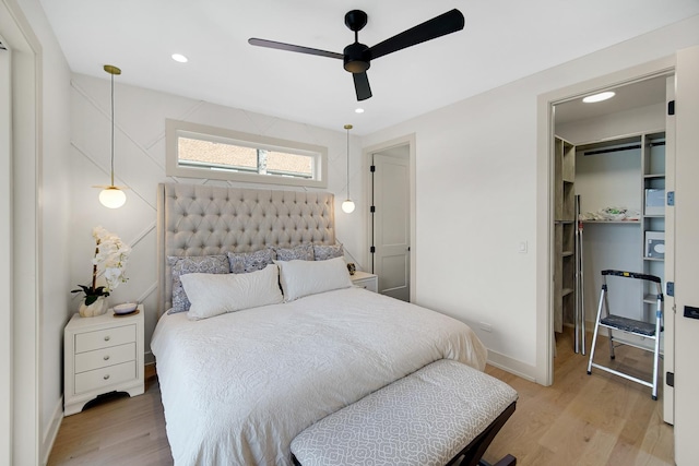 bedroom with ceiling fan, light hardwood / wood-style floors, and a walk in closet