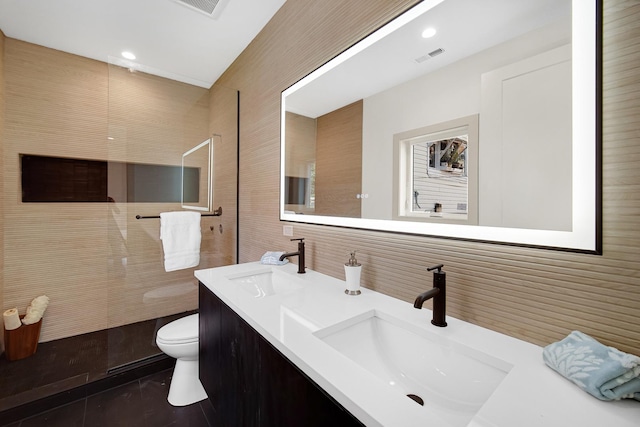 bathroom with vanity, toilet, and a tile shower