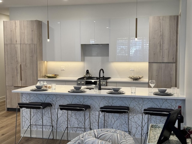 kitchen with white cabinetry, dark hardwood / wood-style floors, a breakfast bar area, and stainless steel range oven