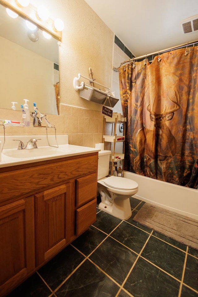 full bathroom featuring shower / tub combo with curtain, tile walls, vanity, tile patterned floors, and toilet