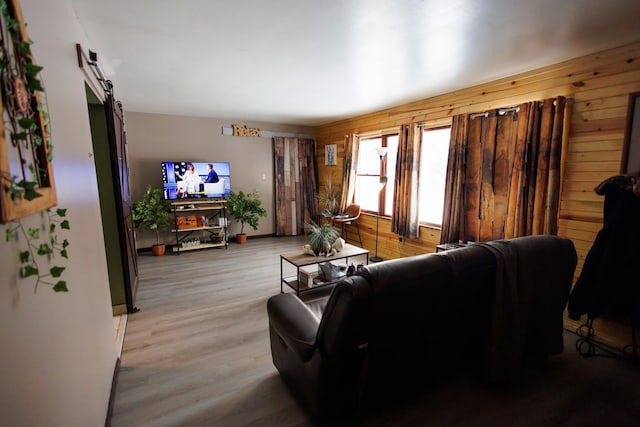 living room featuring light hardwood / wood-style floors, a barn door, and wood walls