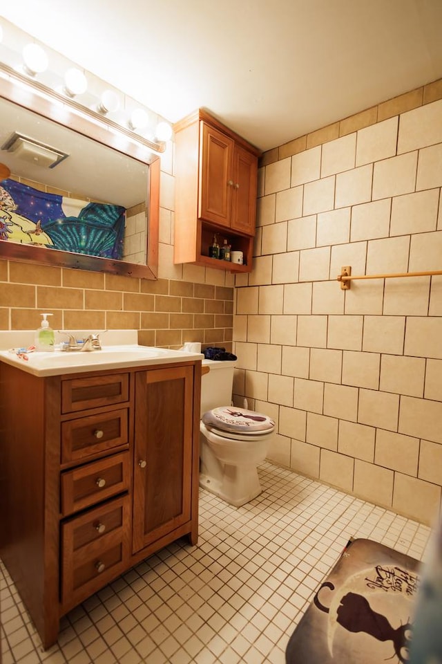 bathroom featuring tile patterned flooring, vanity, tile walls, and toilet