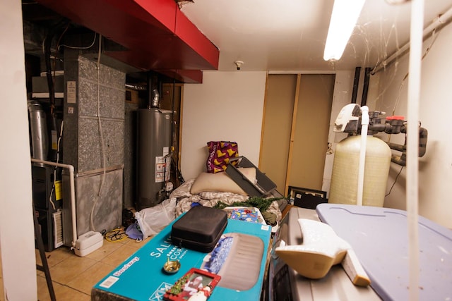 basement featuring water heater and light tile patterned floors