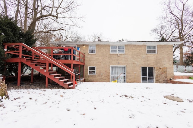 snow covered back of property with a wooden deck