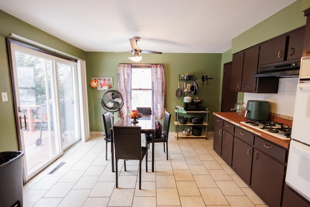 kitchen with light tile patterned floors, ceiling fan, dark brown cabinetry, white gas stovetop, and decorative backsplash