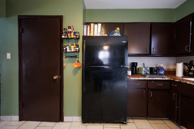 kitchen featuring black refrigerator, decorative backsplash, dark brown cabinets, and light tile patterned flooring