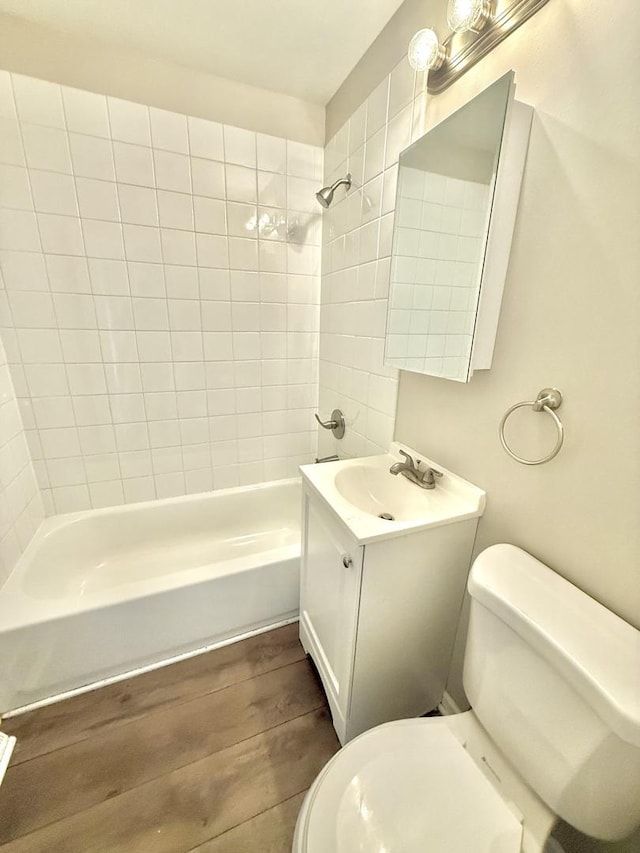 full bathroom featuring hardwood / wood-style flooring, vanity, toilet, and tiled shower / bath combo