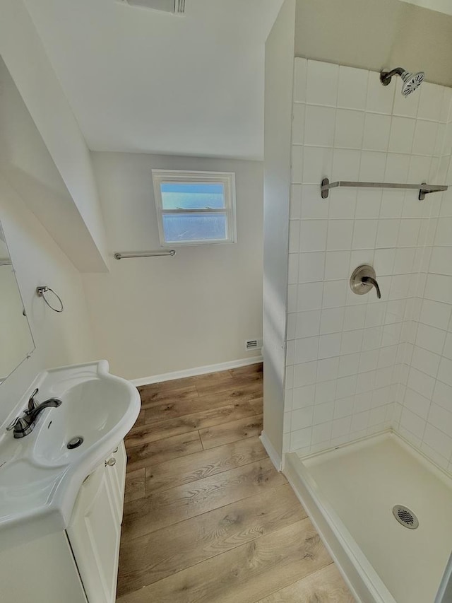 bathroom with vanity, tiled shower, and hardwood / wood-style floors