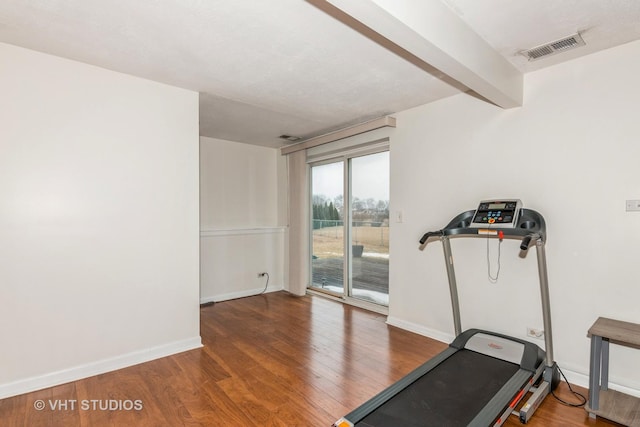 exercise room featuring baseboards, visible vents, and wood finished floors