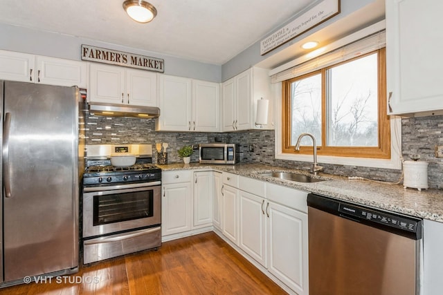 kitchen featuring dark wood-style flooring, appliances with stainless steel finishes, white cabinetry, a sink, and under cabinet range hood