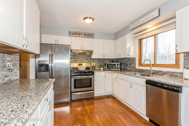 kitchen featuring under cabinet range hood, appliances with stainless steel finishes, white cabinets, and a sink