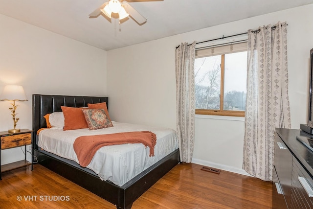 bedroom featuring baseboards, visible vents, ceiling fan, and wood finished floors