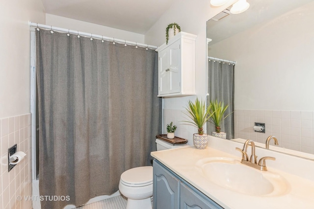 full bathroom with tile walls, toilet, and vanity