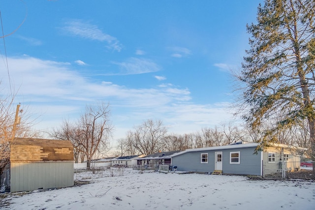 snow covered house featuring a storage shed