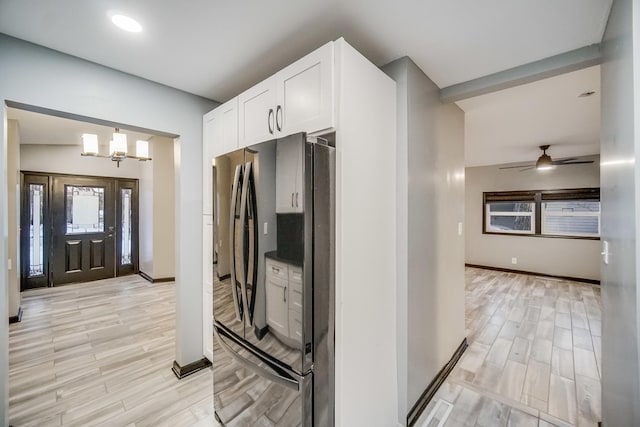 kitchen with white cabinetry, refrigerator, ceiling fan with notable chandelier, and pendant lighting