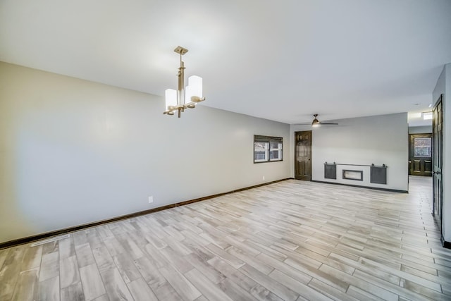 unfurnished living room featuring ceiling fan with notable chandelier and light wood-type flooring