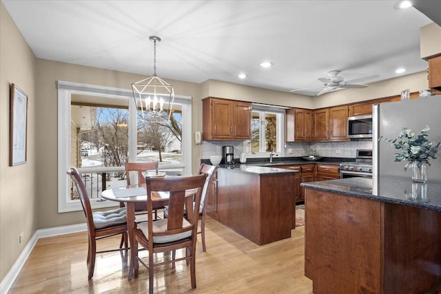 kitchen featuring sink, stainless steel appliances, tasteful backsplash, decorative light fixtures, and light wood-type flooring