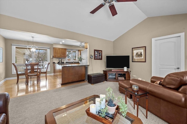 living room with lofted ceiling, ceiling fan with notable chandelier, and light hardwood / wood-style flooring