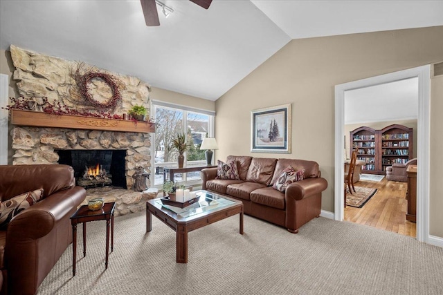 living room with a stone fireplace, lofted ceiling, ceiling fan, and light hardwood / wood-style floors