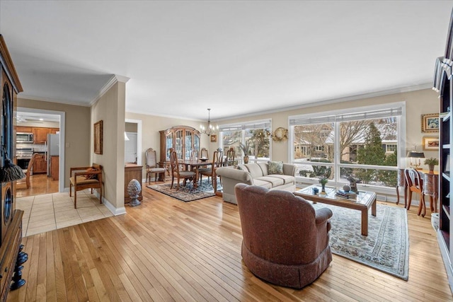 living room featuring ornamental molding, a notable chandelier, and light wood-type flooring