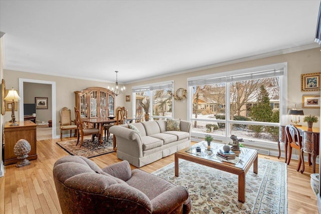 living room with an inviting chandelier, light hardwood / wood-style flooring, and ornamental molding