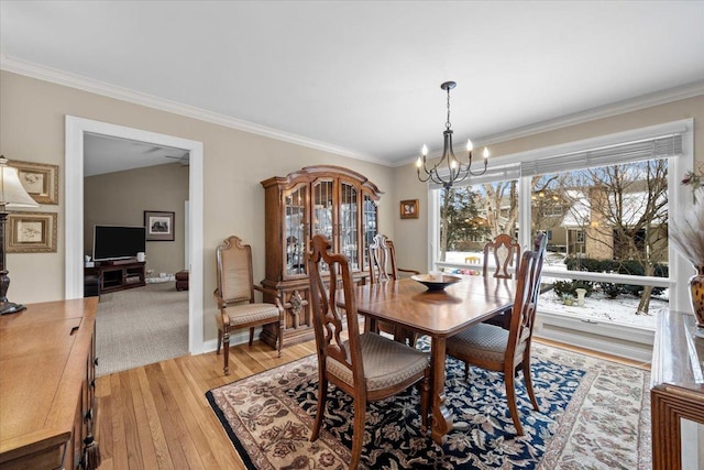 dining area featuring an inviting chandelier, ornamental molding, and light hardwood / wood-style flooring