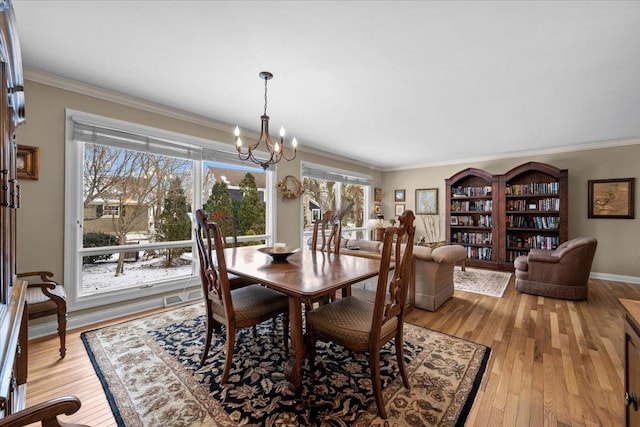 dining space featuring ornamental molding, a notable chandelier, and light hardwood / wood-style flooring