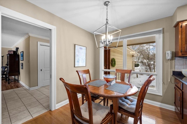 dining area with an inviting chandelier, ornamental molding, and light wood-type flooring