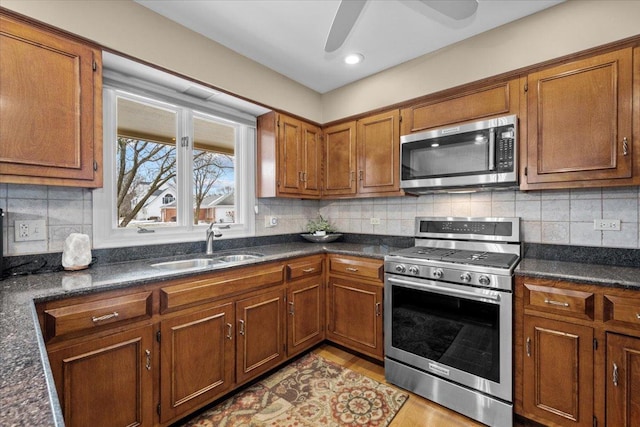 kitchen featuring sink, light hardwood / wood-style flooring, ceiling fan, appliances with stainless steel finishes, and backsplash