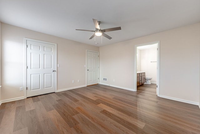 unfurnished bedroom with ceiling fan, ensuite bath, and hardwood / wood-style floors