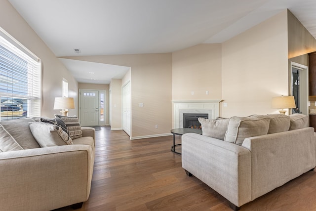 living room with dark wood-type flooring, a high end fireplace, and vaulted ceiling