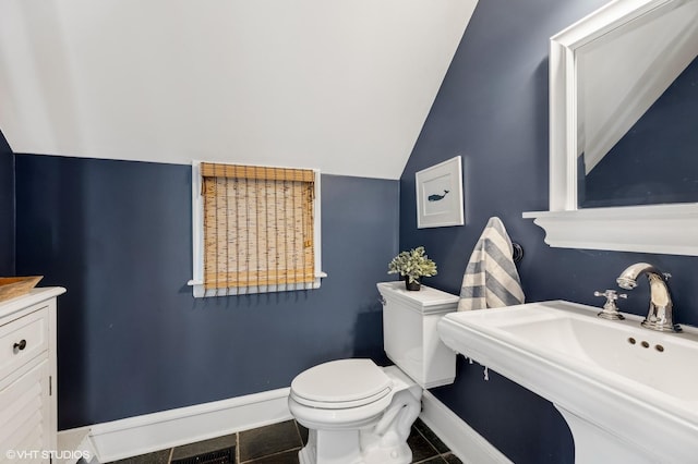 bathroom featuring tile patterned flooring, sink, vaulted ceiling, and toilet