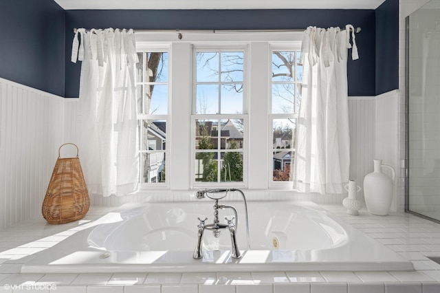 bathroom with plenty of natural light and a relaxing tiled tub