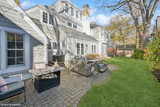 back of property featuring a fire pit, a yard, and a patio