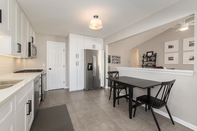 kitchen with lofted ceiling, sink, white cabinetry, stainless steel appliances, and decorative backsplash