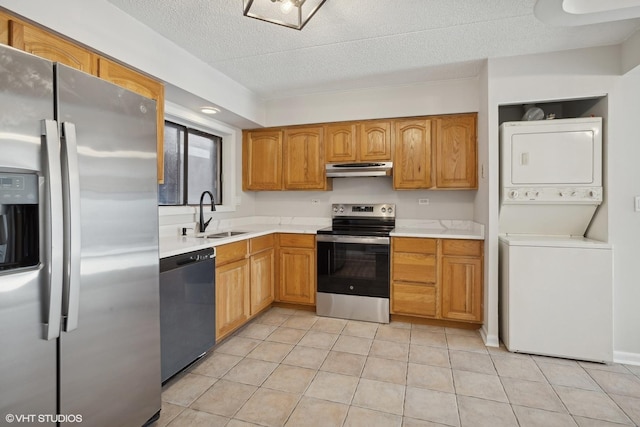 kitchen featuring stacked washer and clothes dryer, sink, a textured ceiling, light tile patterned floors, and appliances with stainless steel finishes