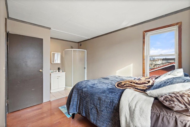 bedroom with hardwood / wood-style floors, crown molding, and ensuite bathroom