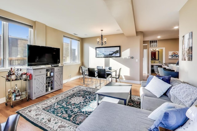 living room with plenty of natural light, an inviting chandelier, and light wood-type flooring