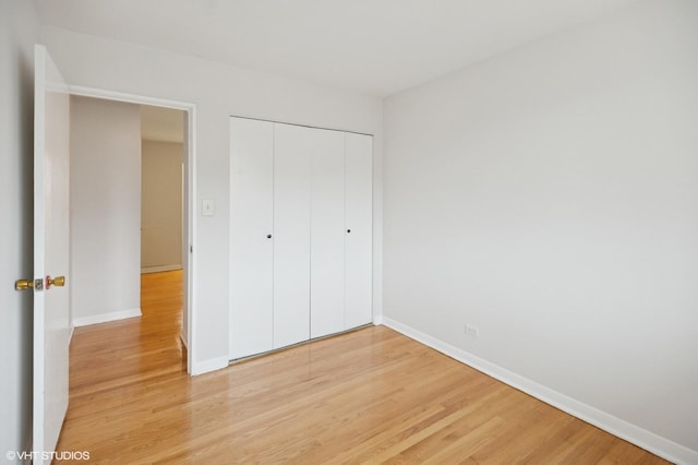 unfurnished bedroom featuring a closet, baseboards, and light wood-style floors