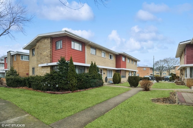 multi unit property with brick siding and a front yard