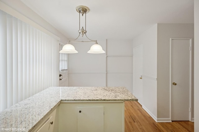 kitchen with light stone counters, baseboards, pendant lighting, and light wood finished floors