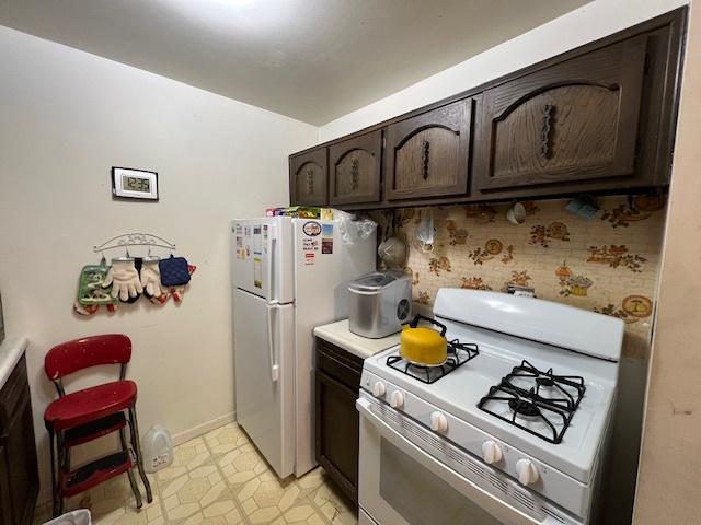 kitchen with dark brown cabinets, backsplash, and white appliances