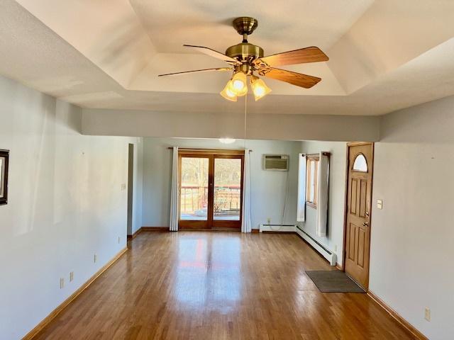 spare room with ceiling fan, a tray ceiling, dark hardwood / wood-style flooring, and a baseboard heating unit