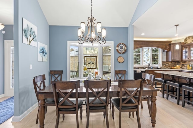 dining room with sink, vaulted ceiling, light hardwood / wood-style flooring, and a notable chandelier