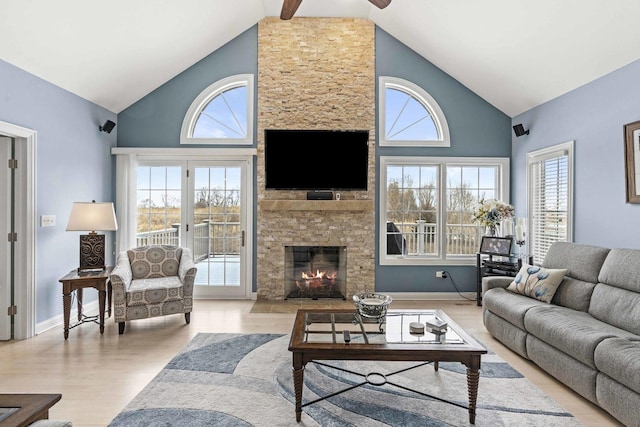 living room featuring a fireplace, high vaulted ceiling, light hardwood / wood-style flooring, and a wealth of natural light