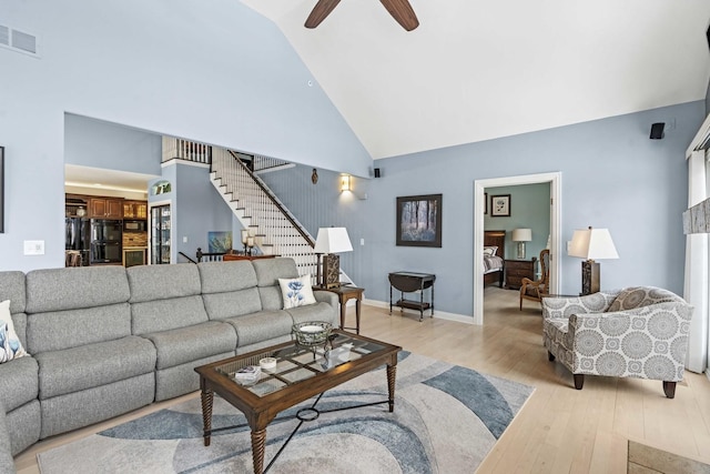 living room with ceiling fan, light hardwood / wood-style floors, and high vaulted ceiling