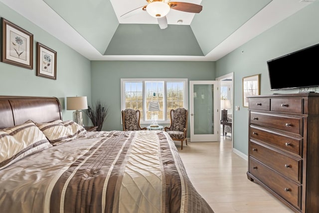 bedroom featuring a tray ceiling, ceiling fan, and light wood-type flooring