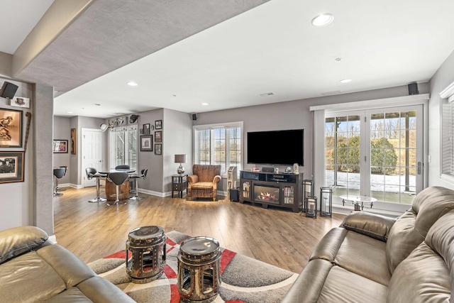 living room featuring french doors, light hardwood / wood-style flooring, and a wealth of natural light