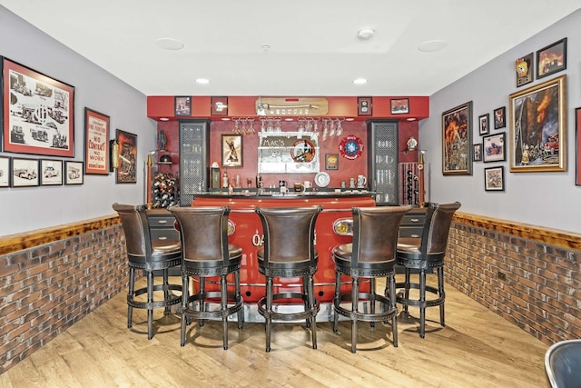 bar featuring hardwood / wood-style flooring and brick wall