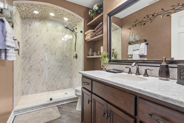 bathroom with vanity, toilet, wood-type flooring, and a tile shower